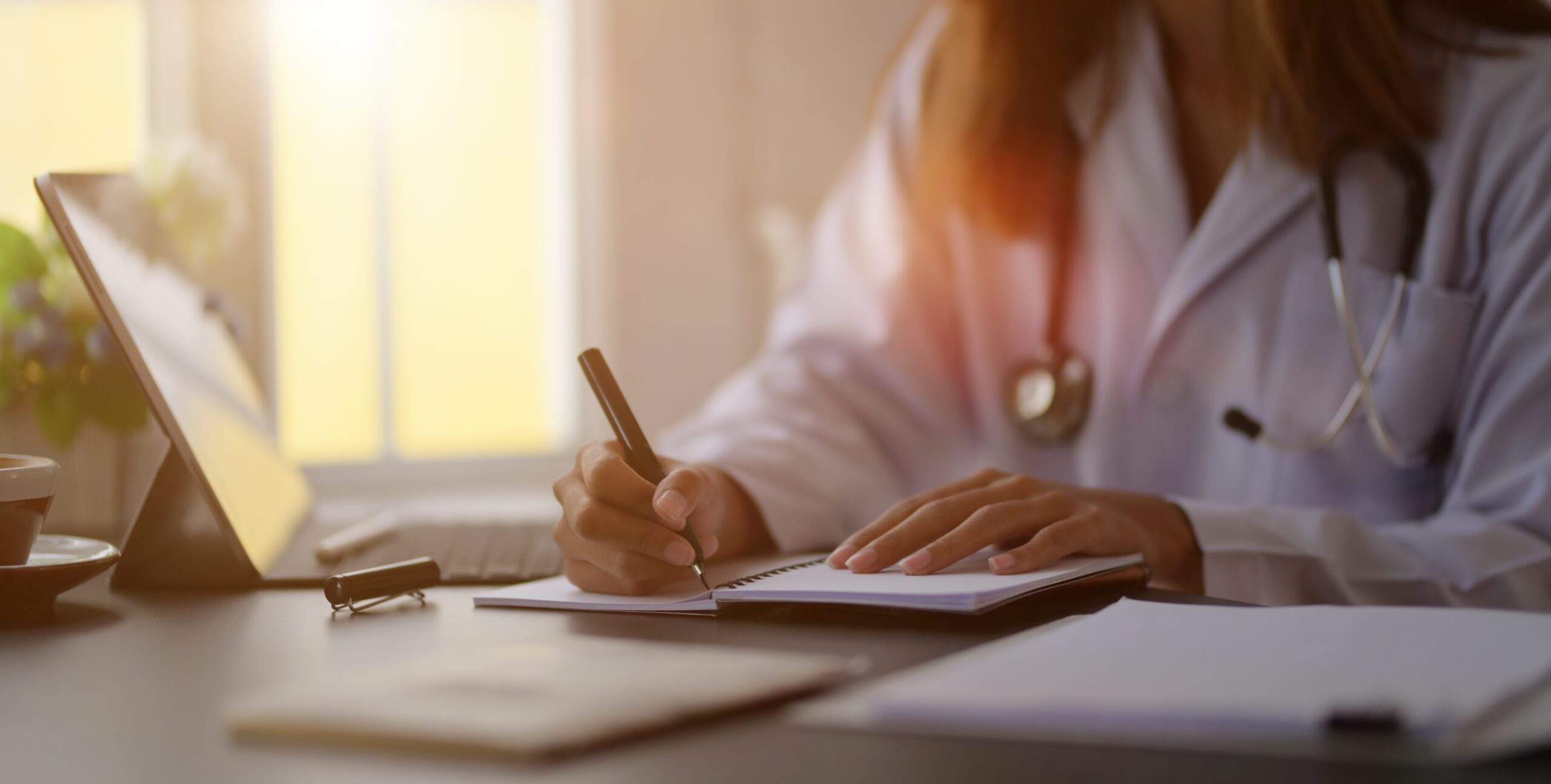 Close-up view of young female doctor writing medical charts with tablet in her office room